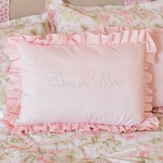 two pink pillows sitting on top of a bed with ruffles around the edges