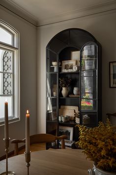 a dining room table with a candle in the center and shelves on either side of it