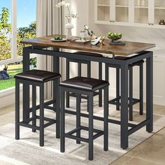 a kitchen table with three stools and a counter top in front of a window