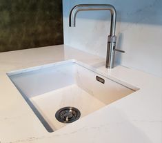 a white sink sitting under a faucet next to a wall mounted faucet