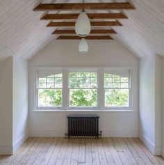 an empty room with a radiator in the center and wooden beams on the ceiling