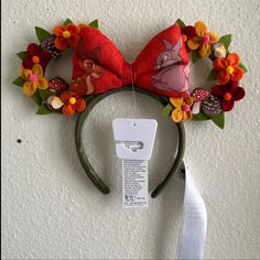 a mouse ears headband with flowers on it and a tag attached to the ear