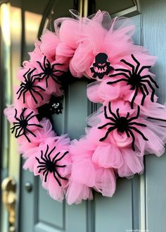 a wreath decorated with pink tulle and black spider webs on the front door