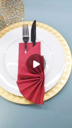 a white plate topped with a red napkin next to a knife and fork on top of a table