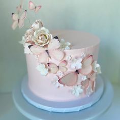 a pink cake with butterflies and flowers on top