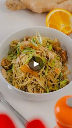 a white bowl filled with food next to an orange and some utensils on a table