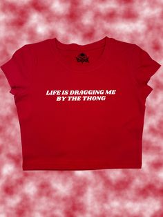 Life Is Dragging Me By The Thong Crop Top - Snug Fit Add a splash of edgy humor to your wardrobe with the "Life Is Dragging Me By The Thong" Crop Top. Whether you're navigating a hectic day or just hanging out with friends, this top is a playful way to express how you're handling the ups and downs of life. You can request a different text color using personalization (shown in second to last slide)! SIZING Please carefully review sizing charts and product descriptions. Due to lighting, phone scre Funny T Shirts For Women, Edgy Humor, Slogan Shirts