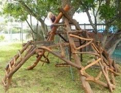 a child playing on a wooden play structure made out of sticks and logs in a park