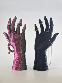 two black and pink hand sculptures with rings on them