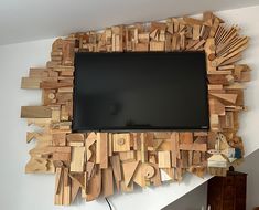 a television mounted to the side of a wall covered in wooden blocks and planks