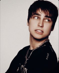 a young man with short hair and piercings looks at the camera while wearing a black shirt