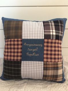 a pillow that has been made with plaid and words on the front, sitting on a bed