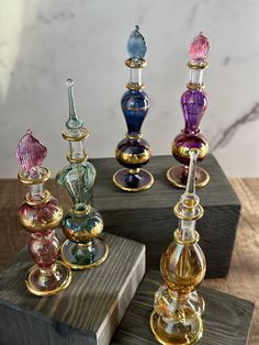 four glass vases sitting on top of a wooden block