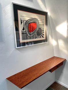 a wooden bench in front of a painting on the wall