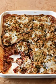 a casserole dish with meat, cheese and sauce in it on a wooden table