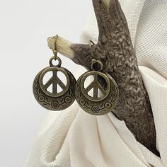 Simple yet unique peace sign earrings. An etched, cutout bronze peace sign charm dangles from a bronze, nickel-free shepherd's hook ear wire. Hippie, retro 70s style earrings.  Nice size for those who prefer shorter earrings at 1-1/8 inches long and 3/4 inches wide. Perfect everyday earrings to wear with jeans. These make an affordable gift idea. Each pair of earrings comes with a soft, flexible, clear back to help keep your earrings securely in place. I have fast shipping (same day or next), pa Affordable Unique Festival Earrings, Peace Sign Earrings Boho, Affordable Handmade Festival Earrings, Affordable Handmade Dangle Charms, Hippie Earrings With Real Medal, Gifts For Hippy, Affordable Handmade Retro Jewelry, Affordable Festival Danglers, Peace Sign Earrings