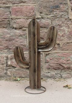 a metal cactus sitting next to a brick wall