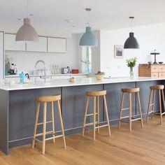 an open kitchen with bar stools next to the counter and dining room table in the background