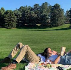 a man and woman laying in the grass reading books while one lays on his back