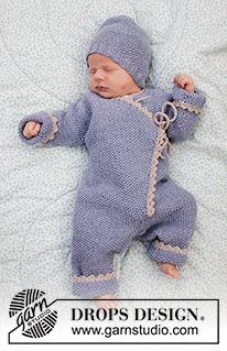 a baby wearing a blue knitted outfit laying on top of a white blanket with chains hanging from it's sides