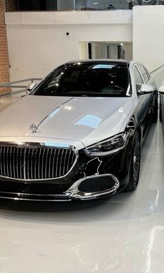 two cars are parked next to each other in a showroom, one is white and the other is black