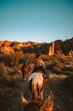 two people are riding horses in the desert