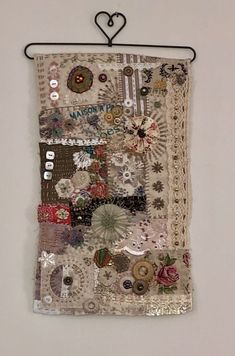 a piece of fabric with buttons and lace hanging on a wall next to a heart