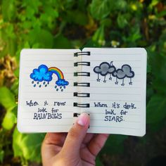 someone is holding up a notebook with drawings on it and the words when it rains look for rainbows