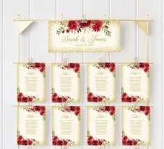 wedding seating chart with red flowers and greenery hanging from gold hooks on a white wall