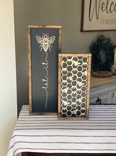 two framed pictures sitting on top of a table next to a black and white striped table cloth