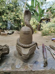 a clay sculpture with a snake on it's head sitting on top of a table