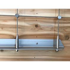 a metal shelf with two hooks on it against a wooden wall and wood planks