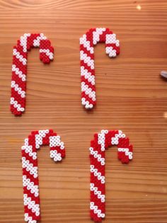 some type of candy canes made out of plastic beads on a wooden surface with the letters spelled out