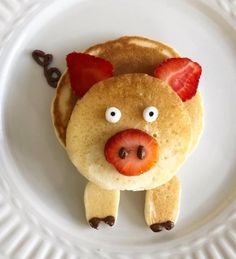 a plate with pancakes shaped like a pig and strawberries on it's face