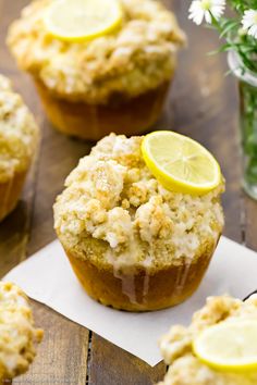 several lemon muffins on a wooden table with flowers in the backgroud