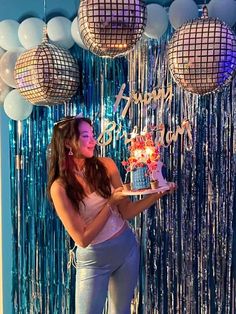 a woman holding a cake in front of some disco balls