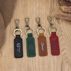 four leather key fobrings sitting on top of a wooden table