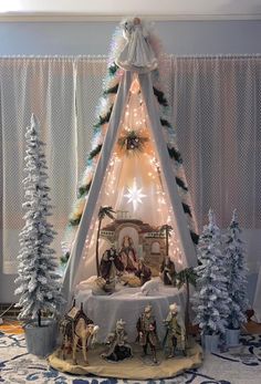 a nativity scene is displayed in front of a christmas tree with lights on it