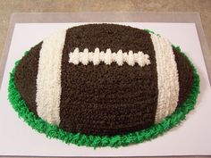 a cake that looks like a football on top of green and white frosted grass