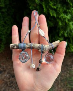 a person holding a piece of jewelry in their hand with a tree branch attached to it