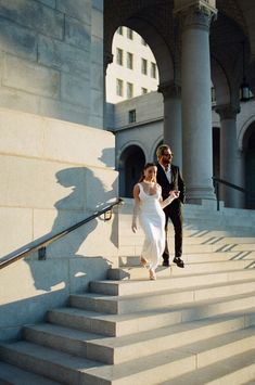 a bride and groom walking down some stairs