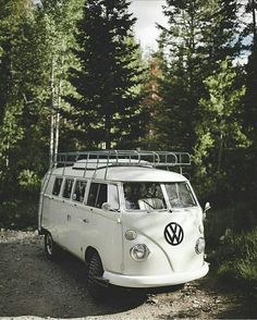 an old vw bus is parked in the woods