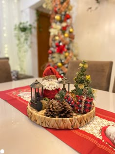 a santa clause figurine sitting on top of a table next to a christmas tree