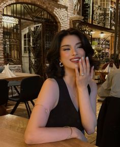 a woman sitting at a wooden table with her hand on her face and looking off to the side