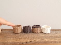 three wicker baskets sitting on top of a wooden table next to a person's finger