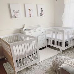 two white cribs in a nursery with pictures on the wall