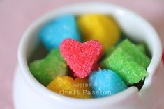 a white cup filled with gummy bears sitting on top of a pink tablecloth