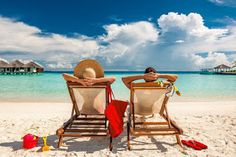 two people sitting in chairs on the beach