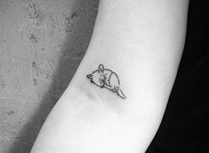 a black and white photo of a small rat tattoo on the left inner arm,