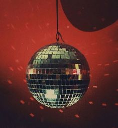 a disco ball hanging from a string in front of a red wall